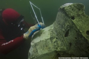Un archeologo misura una colonna sottacqua