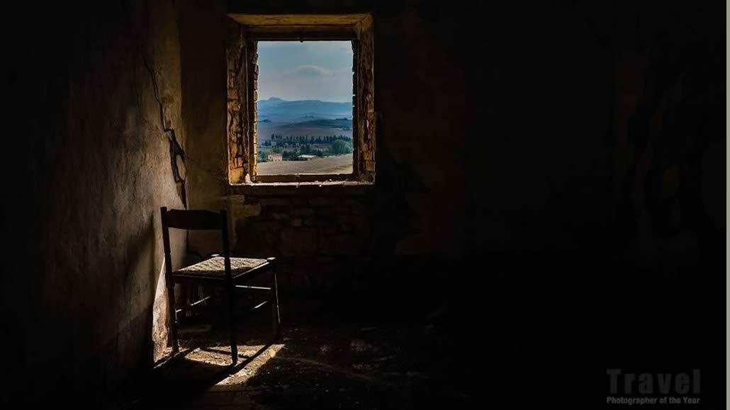Vista da una finestra con una sedia colpita dalla luce del sole (c) Angiolo Manetti